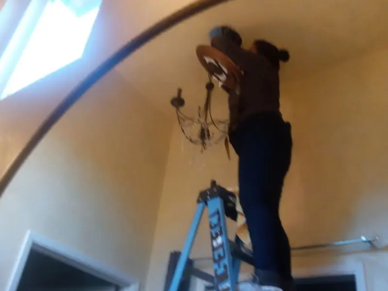 Electrician installing a chandelier in a Barling residence